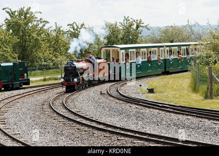 Vue du chemin de fer léger d'Evesham Vale, l'une des attractions familiales d'Evesham Country Park, Worcestershire, montrant le conducteur et les passagers qui contournent un virage de la piste. Ce chemin de fer à vapeur miniature pour passagers a ouvert ses portes en août 2002 avec un écartement étroit de 15 pieds. Banque D'Images