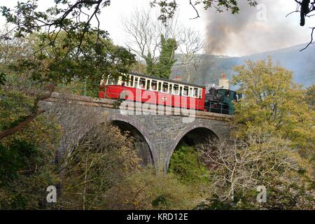 Vue du Snowdon Mountain Railway traversant un pont à Waterfall Halte juste au-dessus de la ville de Llanberis à Gwynedd, au nord du pays de Galles. De la gare de Llanberis, le train passe devant la cascade et commence la montée abrupte jusqu'au sommet de Snowdon. Les passagers peuvent être vus à l'intérieur de la voiture, regardant le paysage. Banque D'Images