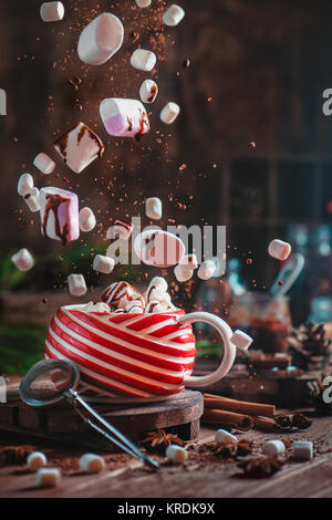 Chocolat chaud de Noël avec le vol, les guimauves et le chocolat. Nouvel An fête scène avec des miettes de chocolat, d'épices et big red mug. Shot dynamique wit Banque D'Images