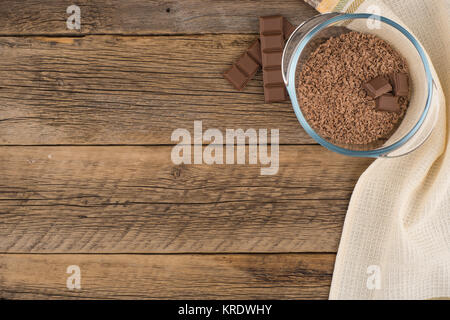 De chocolat râpé dans un bol en verre sur la vieille table en bois. Banque D'Images