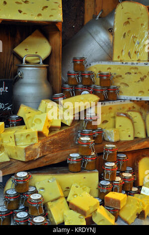 Une sélection f différents fromages avec des chutneys et des cornichons et des bidons de lait sur les étagères en bois sur un marché au fromage décroche à Borough Market à Londres. Banque D'Images