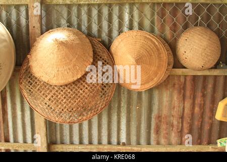 La (Non) chapeaux coniques vietnamiens et bols à riz accroché sur barrière, Delta du Mekong, Vietnam Banque D'Images
