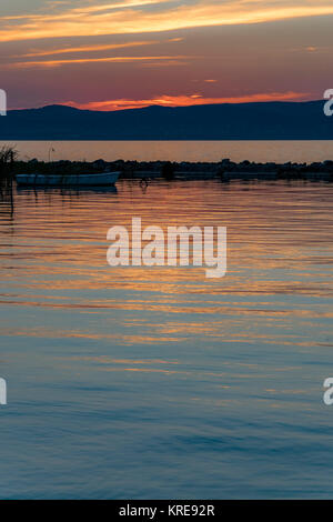 Vue panoramique de coucher de réflexion sur l'eau calme, silhouette de bateau à rames. Orange colorés et coucher du soleil doré et petit bateau au lac Balaton. Banque D'Images