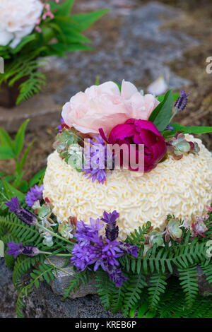 Gâteau de mariage sur le River Rock avec des espèces indigènes de plantes et fleurs à un fleuve Umpqua Nord mariage fugue dans l'Oregon. Banque D'Images