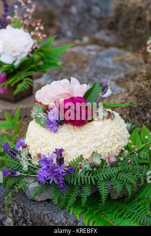 Gâteau de mariage sur le River Rock avec des espèces indigènes de plantes et fleurs à un fleuve Umpqua Nord mariage fugue dans l'Oregon. Banque D'Images