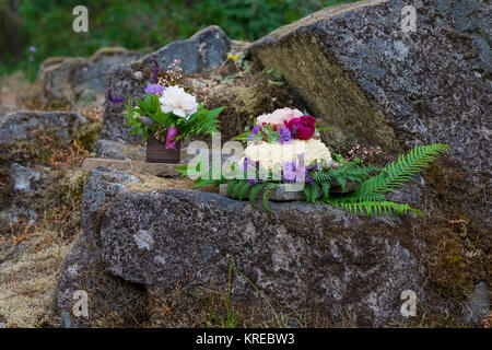 Gâteau de mariage sur le River Rock avec des espèces indigènes de plantes et fleurs à un fleuve Umpqua Nord mariage fugue dans l'Oregon. Banque D'Images