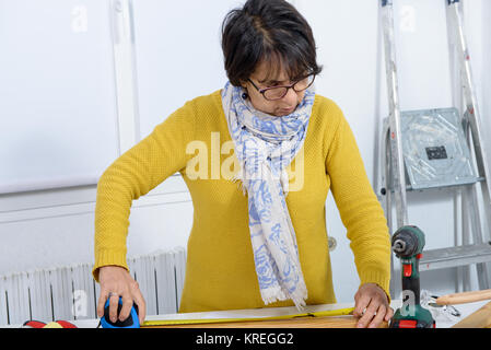 Femme d'âge moyen de faire travailler à la maison bricolage Banque D'Images