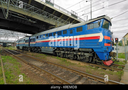 Le train se déplace sur des rails.Au-dessus de lui un pont avec l'autoroute. Banque D'Images