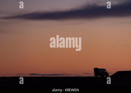 Le camping-car garé sur un paysage rocheux en silhouette contre le ciel au coucher du soleil une colorfuly Banque D'Images