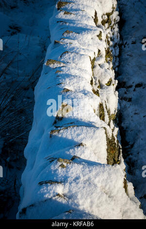 Un mur de pierres sèches couvertes de neige dans le Peak District, Derbyshire, Angleterre. Banque D'Images