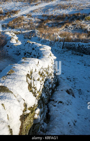 Un mur de pierres sèches couvertes de neige dans le Peak District, Derbyshire, Angleterre. Banque D'Images