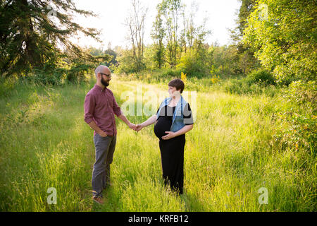 Homme et une femme enceinte dans un champ dans l'Oregon tandis que la jeune fille en est à son troisième trimestre. Le couple est marié et ce mari et femme s'attendent Banque D'Images