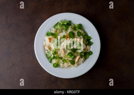 Poulet et riz avec valeriana salade dans une assiette sur la table en bois Banque D'Images