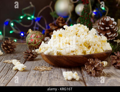 Le maïs soufflé dans un bol en bois sur l'arrière-plan de Noël et Nouvel An décorations, selective focus Banque D'Images