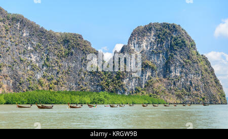 L'île calcaire avec des forêts de mangrove et les bateaux en bois à longue queue à Phang Nga Bay National Park, Thaïlande Banque D'Images