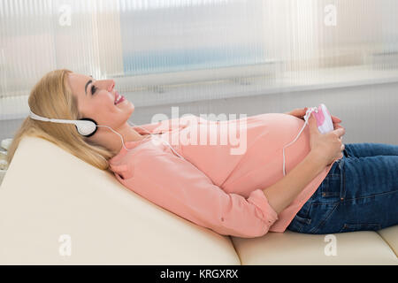 Femme enceinte à écouter au casque battement de coeur Bébé Banque D'Images