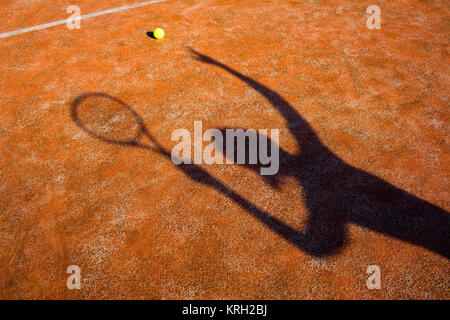 Ombre d'un joueur de tennis en action sur un court de tennis (conceptual image avec une balle de tennis se trouvant sur la cour et l'ombre du joueur placé d'une façon qu'il semble être le jouer) Banque D'Images