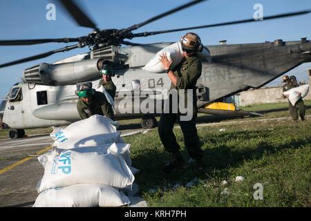 Des soldats de la Marine américaine de décharger des sacs de riz d'un Sikorsky CH-53E Super Stallion hélicoptère pendant une mission d'assistance de secours en cas de catastrophe humanitaire à la suite de l'Ouragan Matthew 6 Octobre 2016 à Les Cayes, Haïti. Banque D'Images