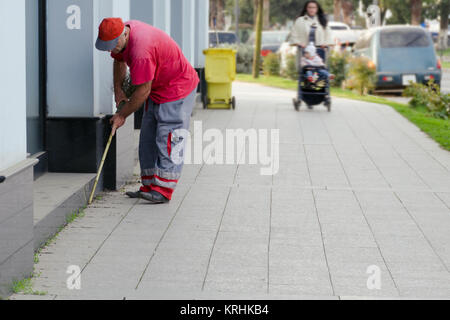 Un nettoyant ville ordures collecte près d'un bâtiment près du trottoir. Banque D'Images