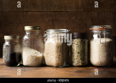 Plusieurs pots dans une ligne remplie avec différents types de riz séché. Fond de bois, copie de l'espace. Banque D'Images