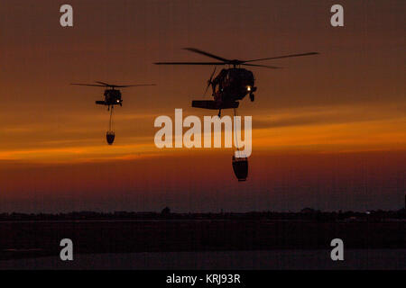 Une paire de Californie National Guard hélicoptères UH-60 Black Hawk de la Compagnie B, 1er Bataillon, 140e Régiment d'aviation, au coucher du soleil retour à l'aéroport de Camarillo de Camarillo, Californie, dimanche, 10 décembre 2017, après avoir effectué leur dernière goutte d'eau de la journée sur le feu Thomas dans le comté de Ventura. (U.S. Air National Guard Banque D'Images