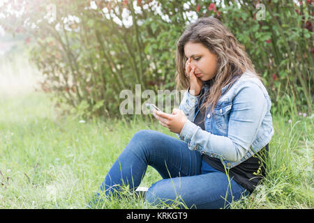 La jeune fille est en train de pleurer en regardant son téléphone intelligent. Banque D'Images