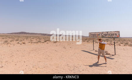 Rehobot, Namibie - 30 août 2016 : une personne avec les bras tendus au tropique du Capricorne balise dans le désert du Namib, Namibie, Afrique. Banque D'Images