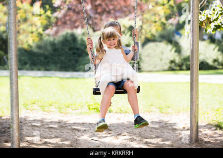 Frère et Sœur bénéficiant sur Swing dans le parc Banque D'Images