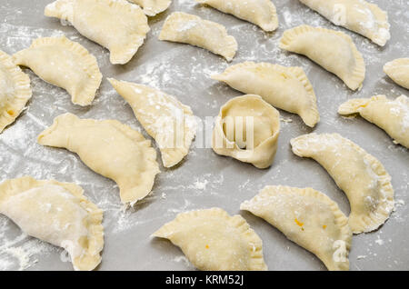 Non-authentique traditionnelle ont organisé la veille de Noël polonais pierogies sur table dans une cuisine moderne avec un ushko, pendant la préparation- prêt à bouillir. Banque D'Images