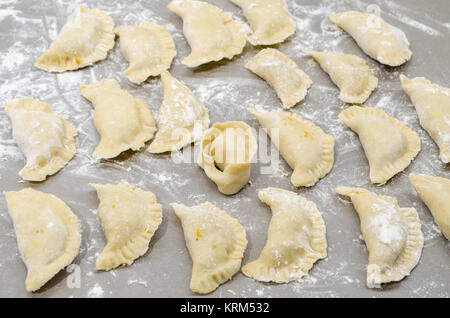 Non-authentique traditionnelle ont organisé la veille de Noël polonais pierogies sur table dans une cuisine moderne avec un ushko, pendant la préparation- prêt à bouillir. Banque D'Images