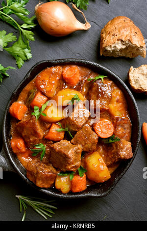 Rencontrez stew, goulash en fonte poêle sur fond sombre. Haut de la vue, télévision lay Banque D'Images