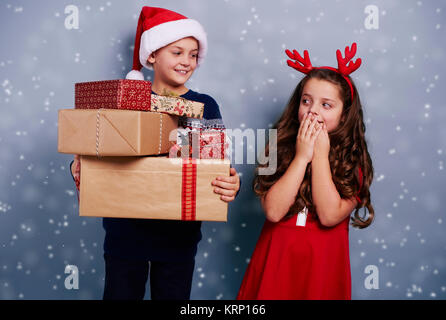 Frères et sœurs heureux avec pile de cadeaux parmi la neige qui tombe Banque D'Images