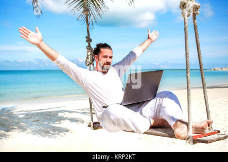 Businessman freelance sur plage avec coffre Banque D'Images