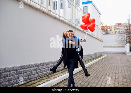 Couple d'amour avec des ballons rouges s'embrasser en plein air sur le ciel  et le fond de la rivière de glace. Lumière du coucher du soleil, vêtements  décontractés noirs. photo – Ballon