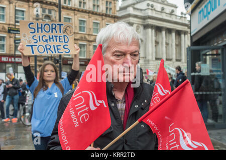 Une femme est titulaire d'un poster de "courte vue des conservateurs derrière un homme portant les drapeaux tous unis comme le mois de mars pour enregistrer des bourses du NHS. Banque D'Images