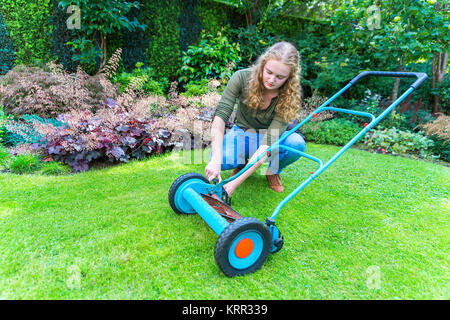 Caucasian woman fixing tondeuse sur l'herbe verte Banque D'Images