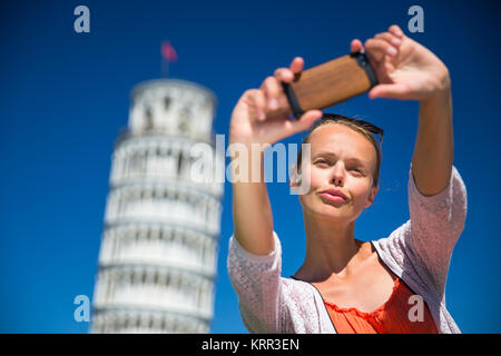 Superbe Jeune femme tenant un téléphone intelligent selfies avec elle en face de la Tour Penchée de Pise, Toscane, Italie (shallow DOF) Banque D'Images