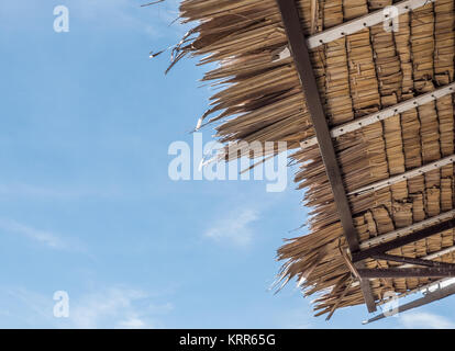 Toit de palme traditionnel avec la structure métallique du gite rural sous le ciel bleu clair. Banque D'Images