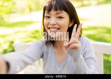 Happy asian woman taking et selfies montrant la paix Banque D'Images