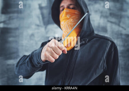Membre de gang à capuchon avec écharpe sur le visage criminel avec tournevis comme arme Banque D'Images