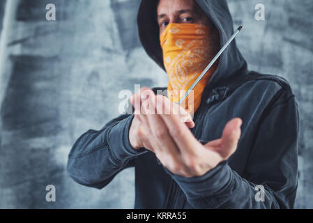 Membre de gang à capuchon avec écharpe sur le visage criminel avec tournevis comme arme Banque D'Images