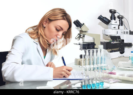 Jeune femme scientifique ou tech écrit résultats des observations en laboratoire de recherche microsopic Banque D'Images