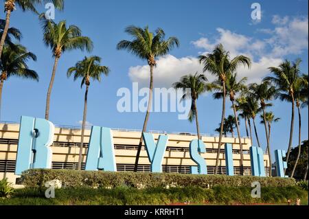 Bayside signe avec palmiers tropicaux, ciel bleu et édifices urbains, en dehors du marché Bayside à Miami, Floride, USA. Banque D'Images