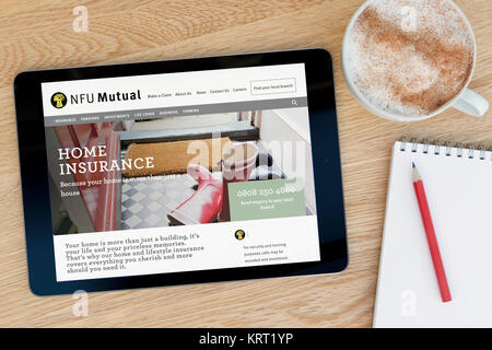 Le site web mutuelle NFU sur un iPad tablet device qui repose sur une table en bois à côté d'un bloc-notes et un crayon et une tasse de café (rédaction uniquement) Banque D'Images