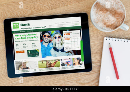 La Banque TD Site sur un iPad tablet device qui repose sur une table en bois à côté d'un bloc-notes et un crayon et une tasse de café (rédaction uniquement) Banque D'Images