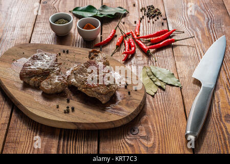 Deux steak cuit avec quelques épices sur table en bois. Banque D'Images