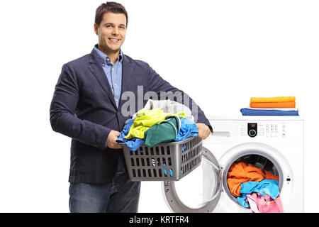 Guy élégante tenant un panier de blanchisserie remplis de vêtements en face d'un lave-linge isolé sur fond blanc Banque D'Images