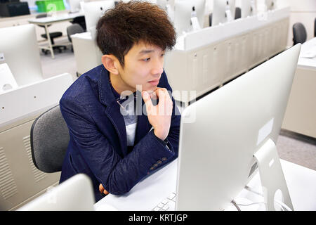 Young man using computer in classroom Banque D'Images