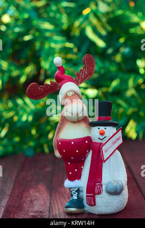 Le renne de Noël avec bonhomme de jouet sur fond vert avec bokeh flou Banque D'Images