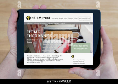 Un homme se penche sur le site web mutuelle NFU sur son iPad tablet device, tourné contre une table en bois page contexte (usage éditorial uniquement) Banque D'Images